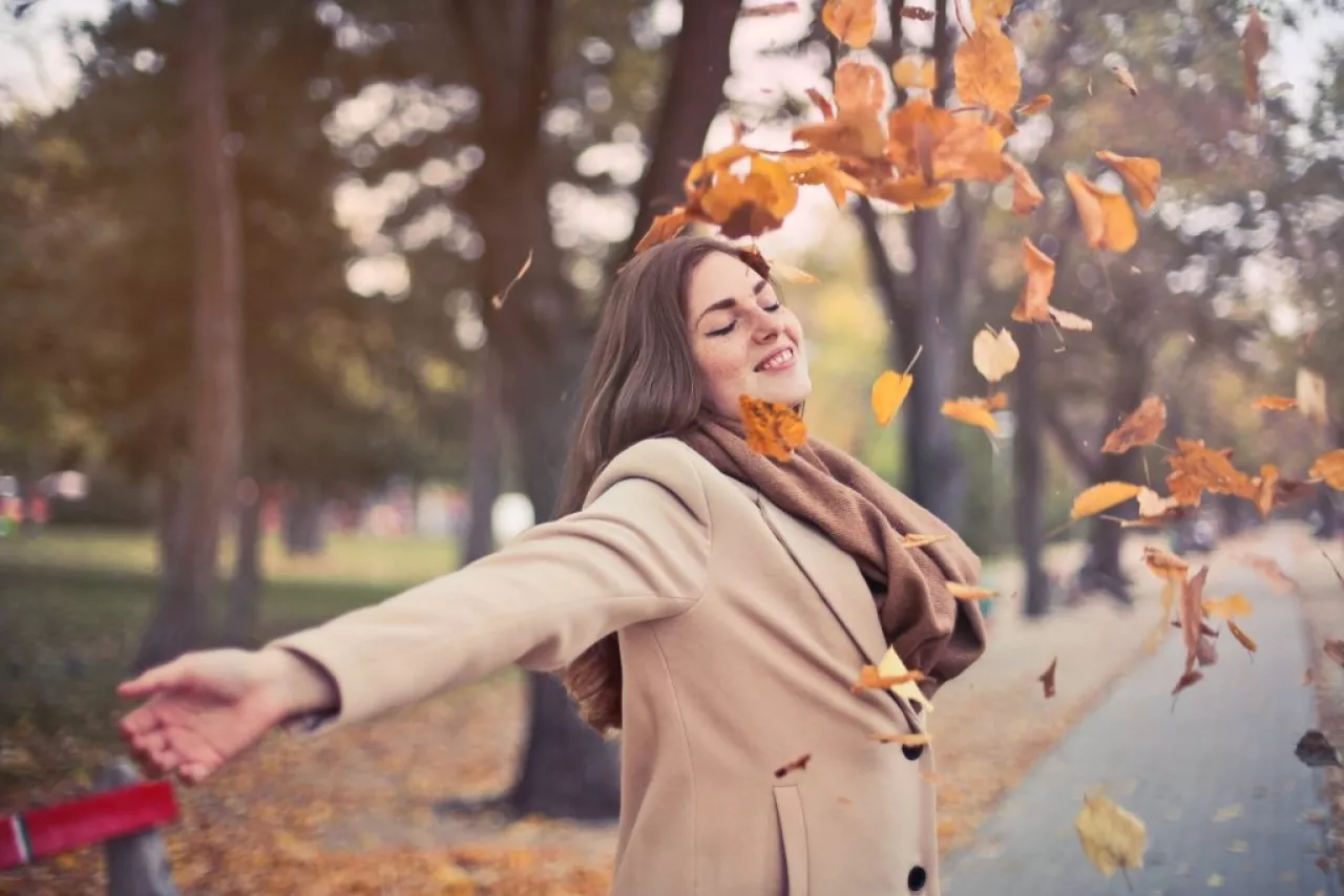 žena v kabáte a jesenné listy
